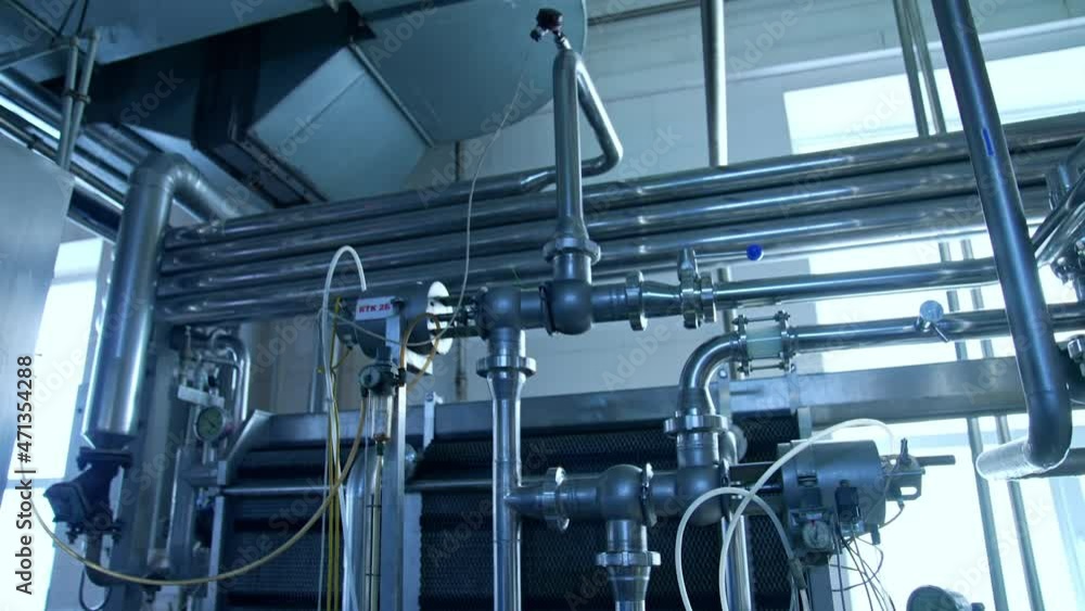 Silver stainless pipelines at a dairy factory. Tubes and pipes of different diameter and controller box in the modern milk enterprise. Close up. Silver stainless pipelines at a dairy factory. Tubes and pipes of different diameter and controller box in the modern milk enterprise. Close up.