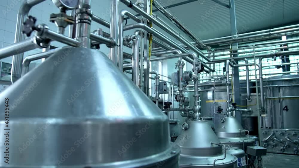 Big cisterns for storing and fermenting milk at diary factory. Stainless steel pipes crossing and connecting reservoirs with each other. Close up. Big cisterns for storing and fermenting milk at diary factory. Stainless steel pipes crossing and connecting reservoirs with each other. Close up.