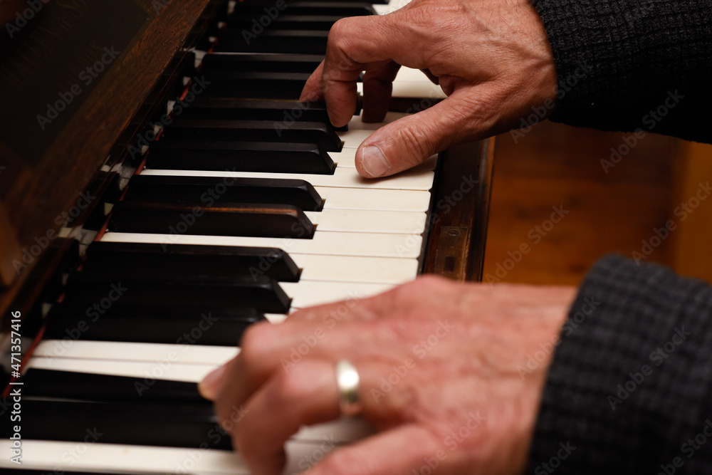 Mature male hands playing piano with focus on hands and keyboard