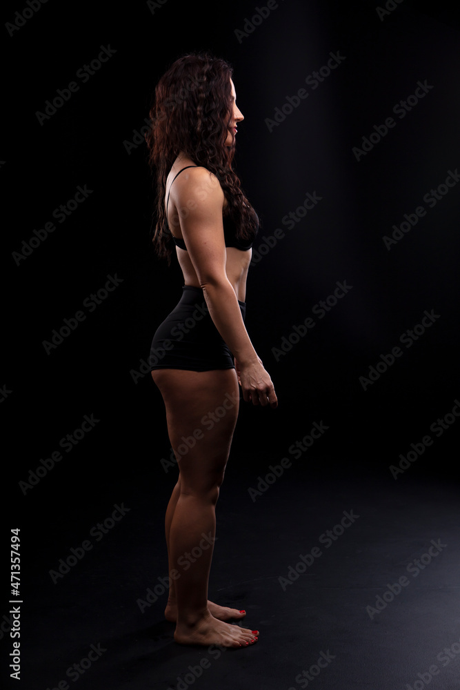 Fototapeta premium Portrait of beautiful athletic woman with long curly black hair. Bodybuilding
