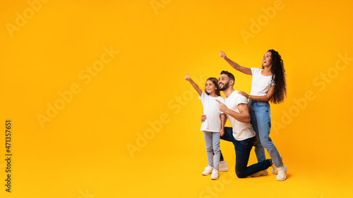 Excited Middle-Eastern Family Pointing Finger Aside Over Yellow Background, Panorama photo