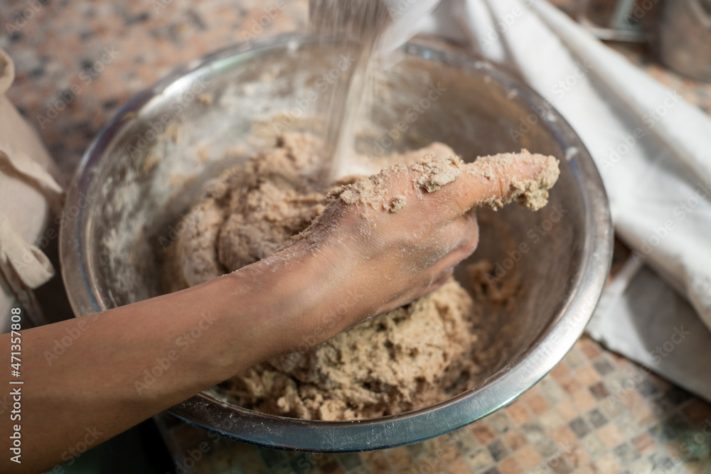 Fototapeta premium Young female preparing vegetarian bread dough on the table. Vegetarian meal concept. Close up.