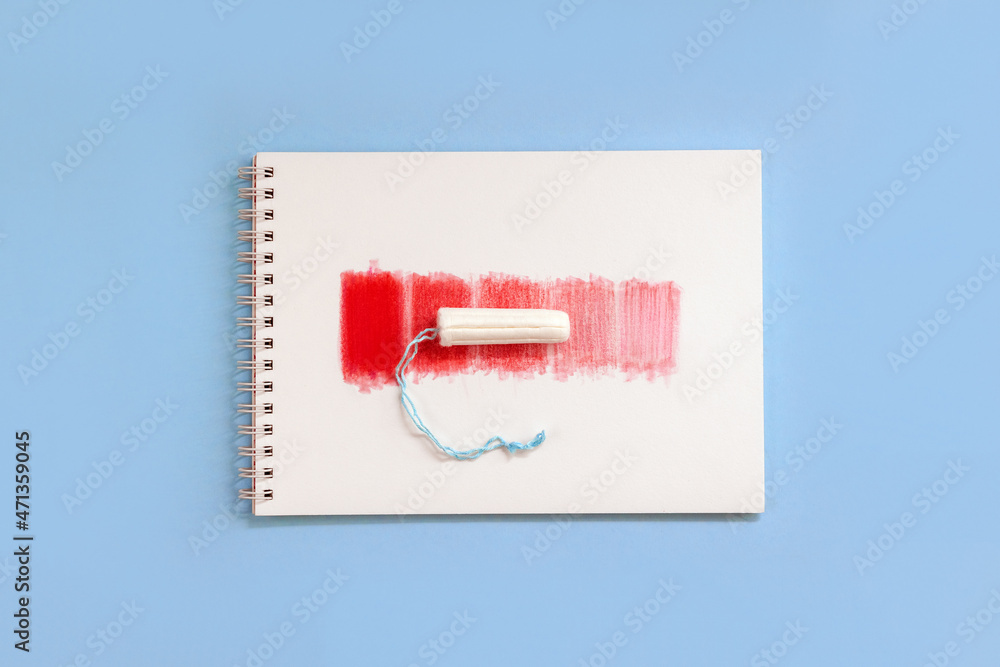 Notebook with red rectangles and feminine hygiene tampon. Concept intensity of menstrual flow. Top view Notebook with red rectangles and feminine hygiene tampon. Concept intensity of menstrual flow. Top view