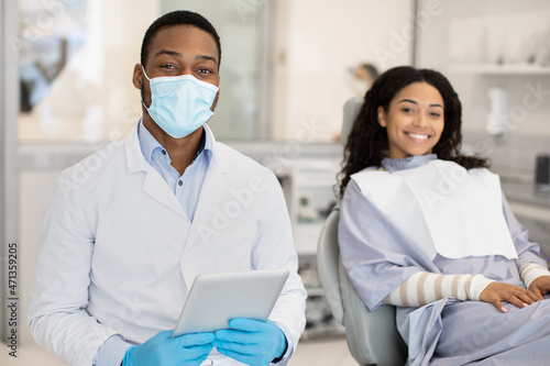 Dental Services. Black Dentist And Female Patient Posing In Modern Clinic Interior