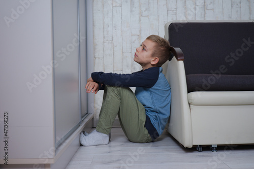 mały chłopak siedzi oparty o fotel, jest smutny © ftomasz