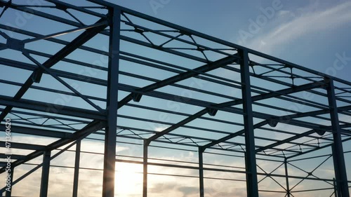 Metal construction - steel frame silhouette of unfinished industrial hall. Structure (framework) consisting of iron girders and beams meant to support the roof with sun shining through the grid.