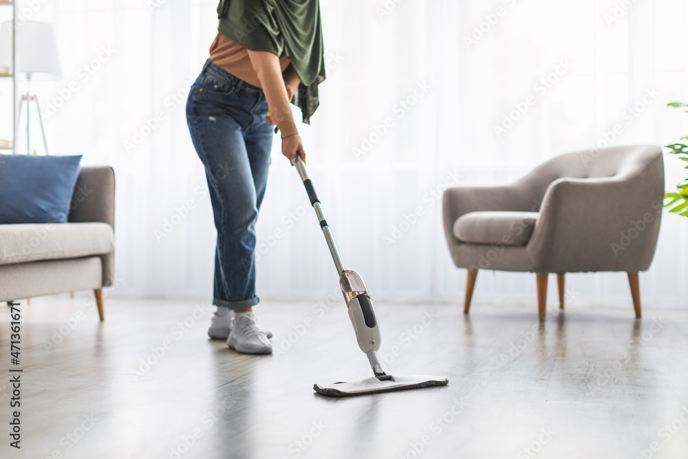 Low section of muslim woman cleaning floor with spray mop