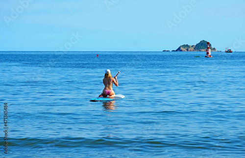 A woman sits and rolls on surfboard
