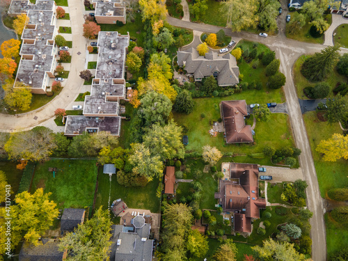 Aerial view of residential neighborhood in Northfield, IL. Lots of trees starting to turn autumn colors. Large residential homes, some with solar panels. Meandering streets
