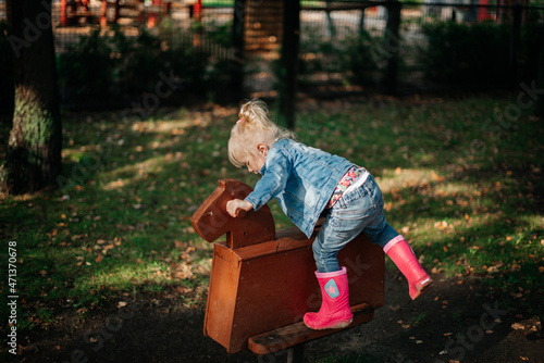 kleines Mädchen klettert auf ein Holzpferd © Alena Vilgelm