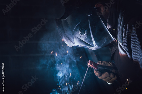 Welder working in a factory welding with an electrode