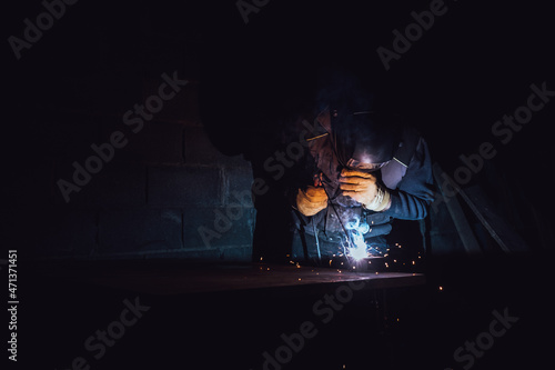 Welder welding a metal plate with an electrode in a factory