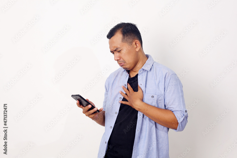 Attractive young Asian man reading texting chatting on his phone, bad news, sad crying expression Attractive young Asian man reading texting chatting on his phone, bad news, sad crying expression