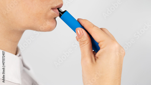 Caucasian woman smokes disposable vape on white background. Alternative device for smoking.