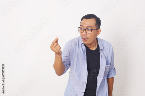 Funny asian man standing while picking something. Isolated on white