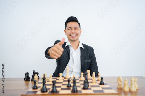Man's thumbs up in suit playing chess