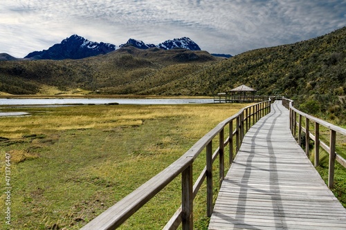 Long wood bridge leading to lake house and the Rumiñahui Volcano surrounded by the Andes mountains of Ecuador in the Cotopaxi Volcano National Park photo