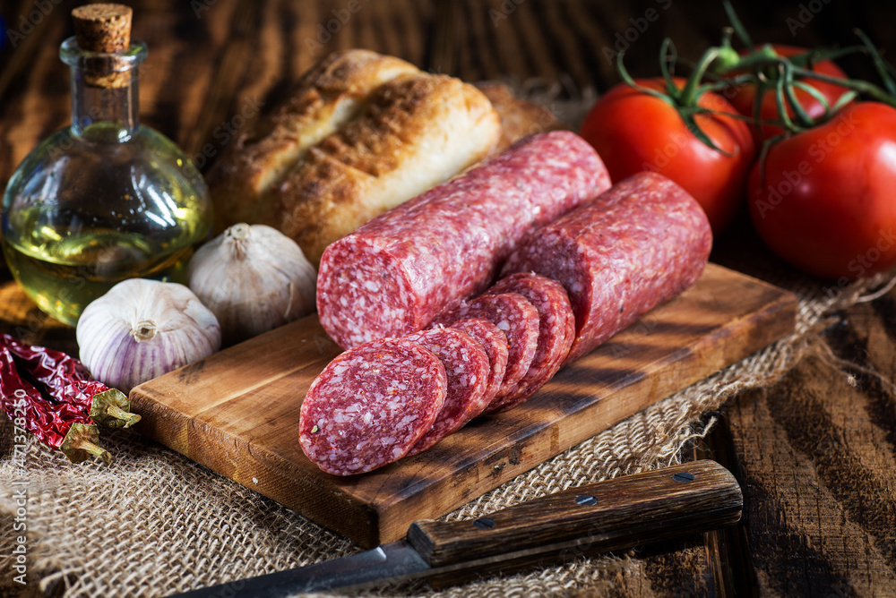 sliced salami on a cutting board with bread and and garlic. sliced salami on a cutting board with bread and and garlic.