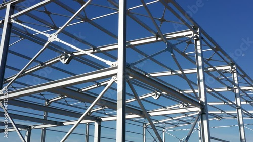 Metal construction - steel frame of unfinished industrial hall. Structure (framework) consisting of iron girders and beams meant to support the roof isolated against blue sky on a sunny day.