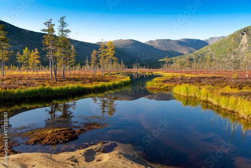 Russia. Magadan Region. A beautiful forest lake against the backdrop of the Big Anngachak mountain range. Autumn in the vicinity of Lake Jack London. © voldemar992