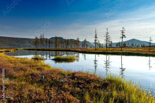 Russia. Magadan Region. A beautiful forest lake against the backdrop of the Big Anngachak mountain range. Autumn in the vicinity of Lake Jack London.