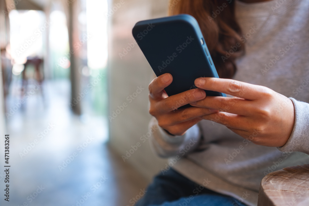 Closeup of a young woman holding and using mobile phone