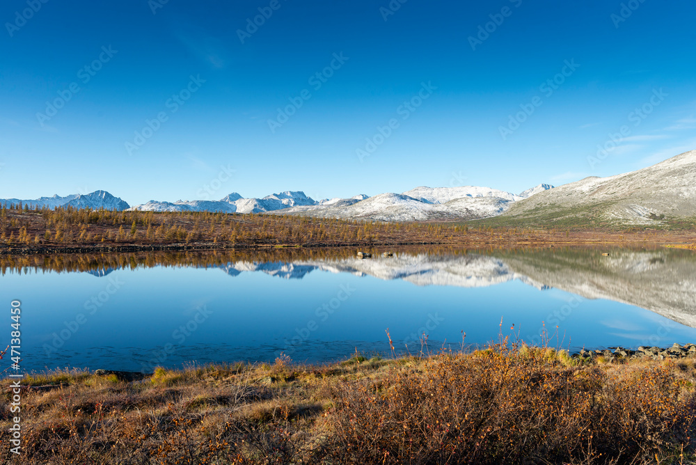 Russia. Magadan Region. A beautiful forest lake against the backdrop of the Big Anngachak mountain range. Autumn in the vicinity of Lake Jack London.   
