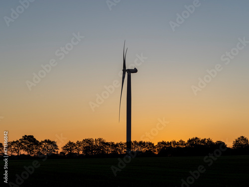A wind turbine. The generator and base of the wind turbines. Renewable energy. Electrical windmills. General contest of green energy. Turbine working at sunrise. Warm colors