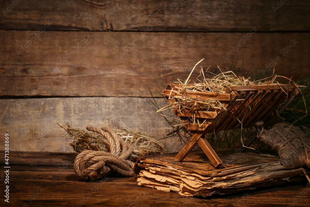 Manger with hay and old book on wooden background. Concept of Christmas