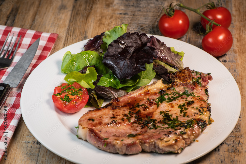 Recipe for grilled pork chop, maple syrup and fresh cilantro marinade, parsley, garlic, served with a salad.