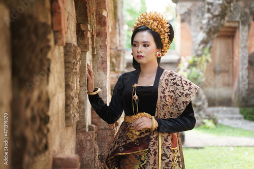 Woman wearing Balinese kebaya standing near a relief fence