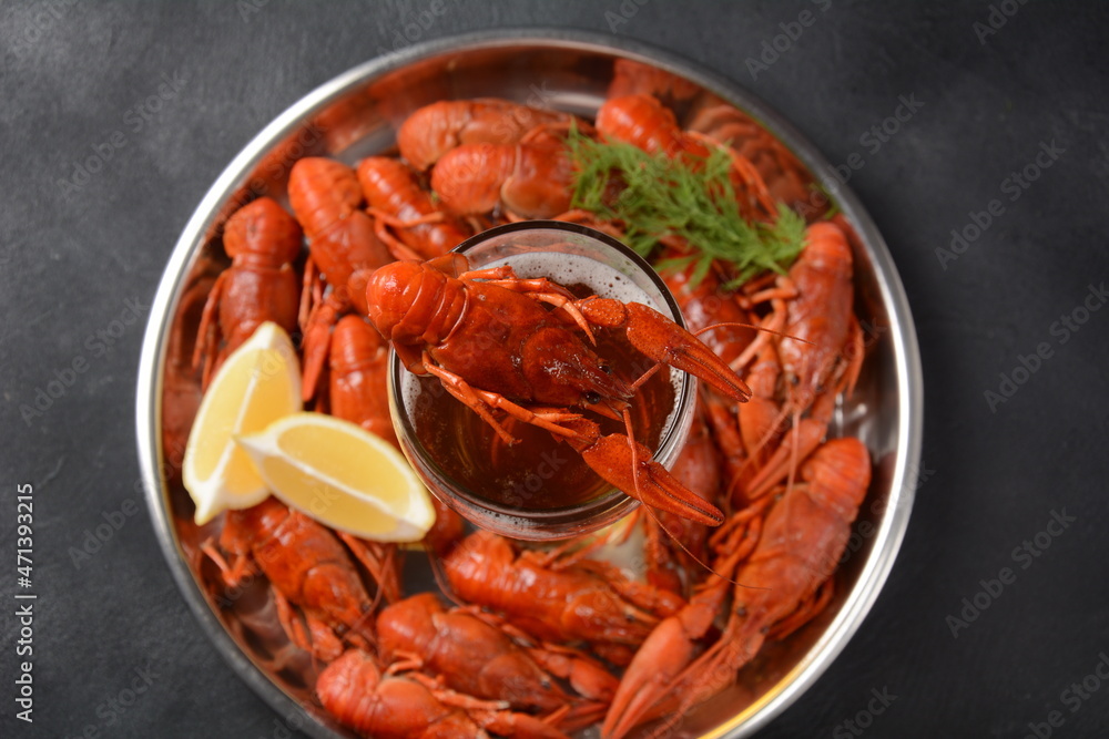 Red boiled crawfishes on table in rustic style. Asian Chinese Food Spicy Crayfish on an iron plate with a mug of beer. Red boiled crawfishes on table in rustic style. Asian Chinese Food Spicy Crayfish on an iron plate with a mug of beer.