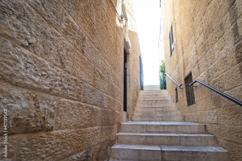 Narrow stone steps in an alley in the Jewish Quarter, with a handle for accessibility for the disabled, in the Old City of Jerusalem, Israel.