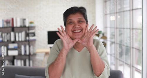 Mature 60s Asian woman dancing with happy and cheerful action during listening to music alone in home living room. Concept of happiness lifestyle and good mental health of senior retirement people.