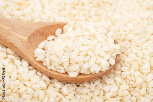 White sesame seeds organic in wooden spoon on white background. Health food concept.