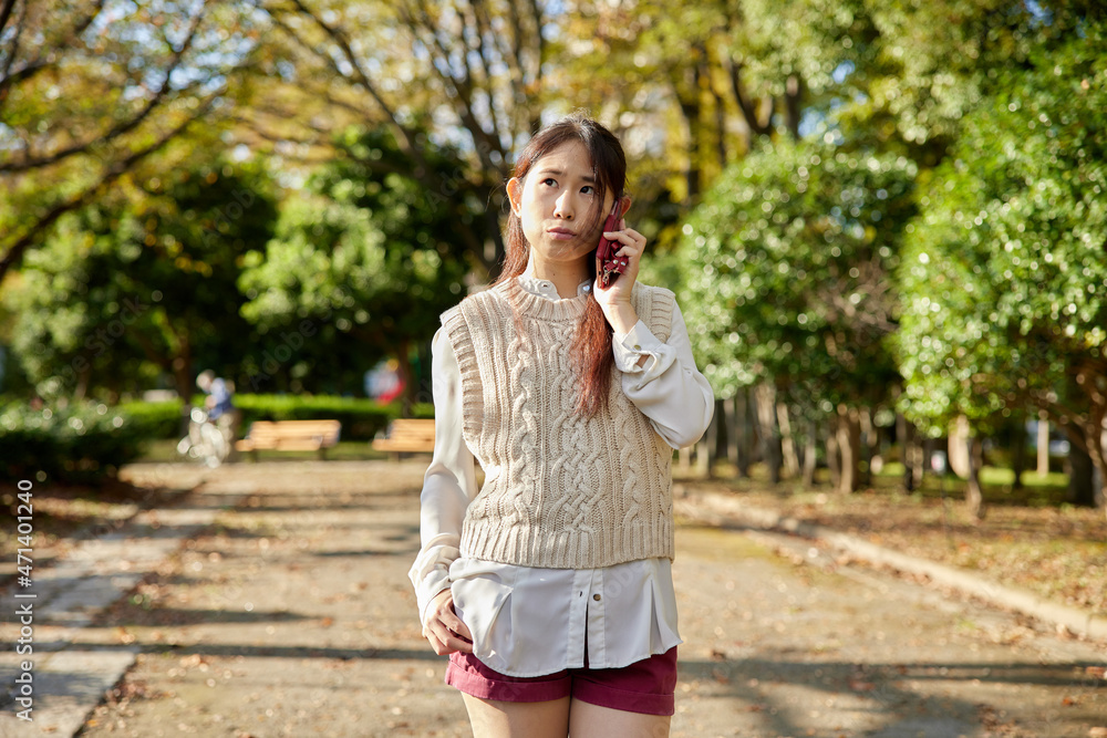 公園の中で電話をかけるアジア人女性