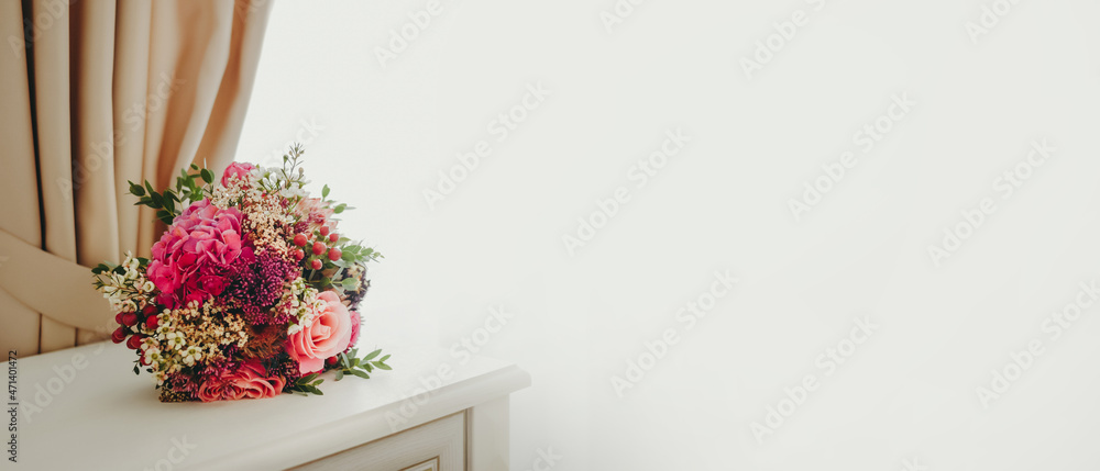 Bridal bouquet, roses, protea, berries on a white chest of drawers. Banner, white background.