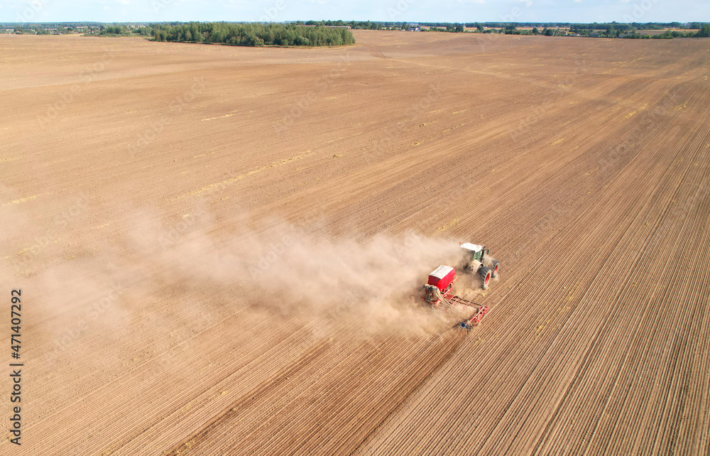 Tractor sowing seed onto at field. Planting Equipment and Farm Implements and Machine. Mini Agricultural tractor on seeds sowing at farmers country, aerial view. Farming and seeding concept.