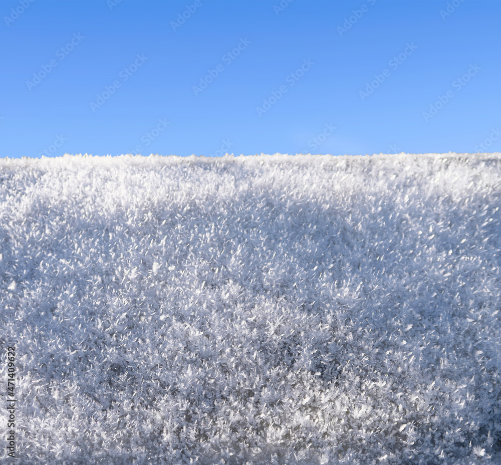 Close-up of snowflakes in the sun on a blurry background. Bright snow, frost sparkles in the sun.