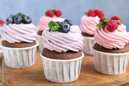 Sweet cupcakes with fresh berries on wooden board, closeup