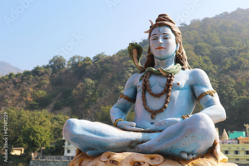 Lord Shiva in the lotus position on the banks of the Ganges river against the background of mountains and sky.