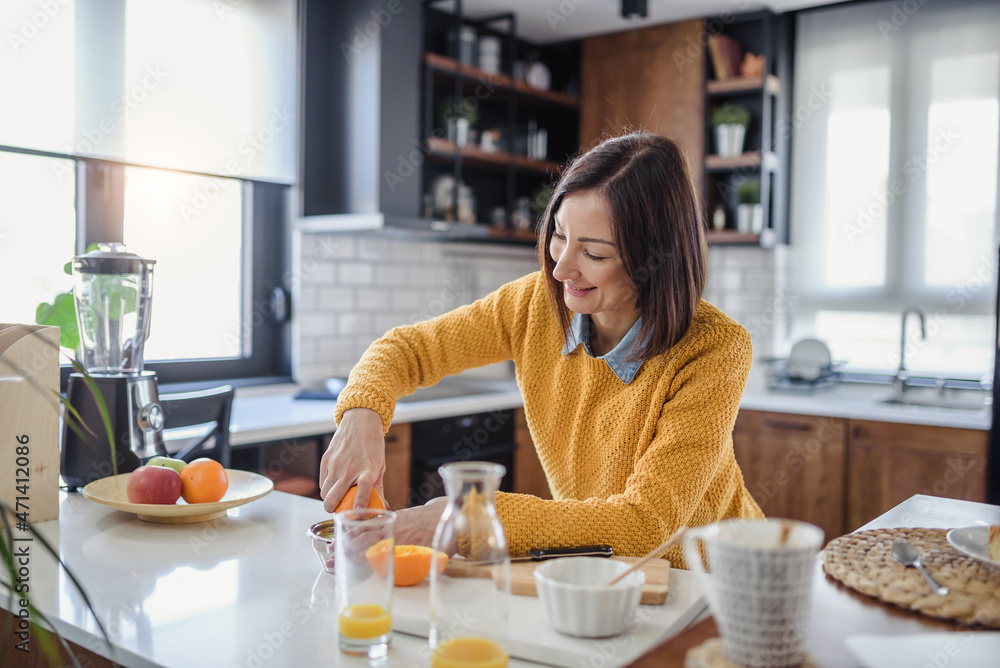 Young beautiful woman preparing healthy fruit juice for breakfast at home before work Young beautiful woman preparing healthy fruit juice for breakfast at home before work
