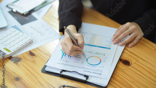Businesswoman checking financial data chart report paper at her desk