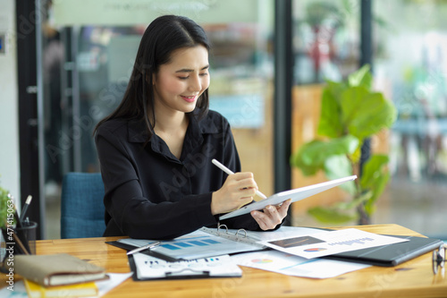 A female financial assistant taking some notes on a tablet.