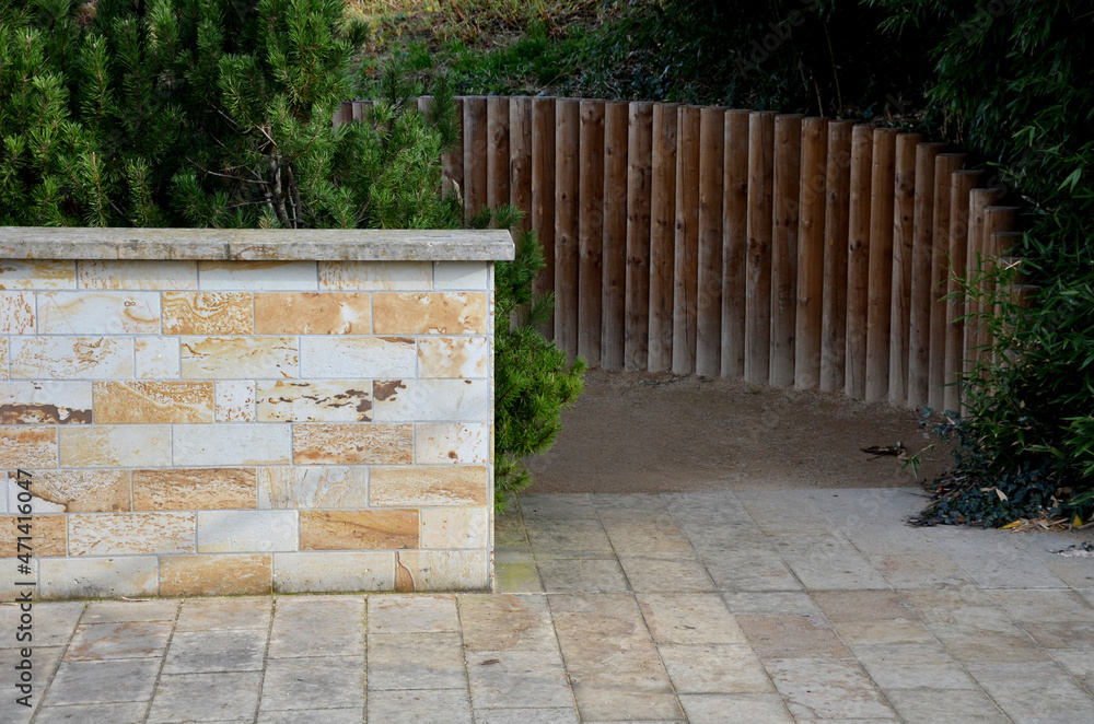 wooden palisade from the poles of the retaining wall of the slope. terrace with a stone wall of sandstone beautiful textures. smooth cladding in the shape of an arch with a roof