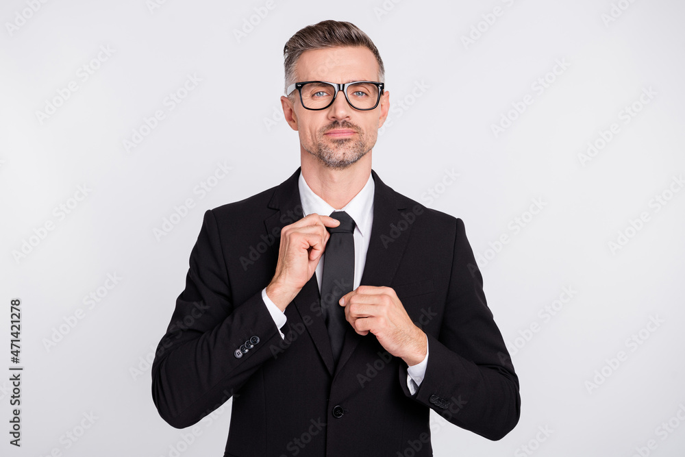 Photo of handsome intelligent young ceo agent wear black jacket spectacles adjusting tie isolated grey color background Photo of handsome intelligent young ceo agent wear black jacket spectacles adjusting tie isolated grey color background