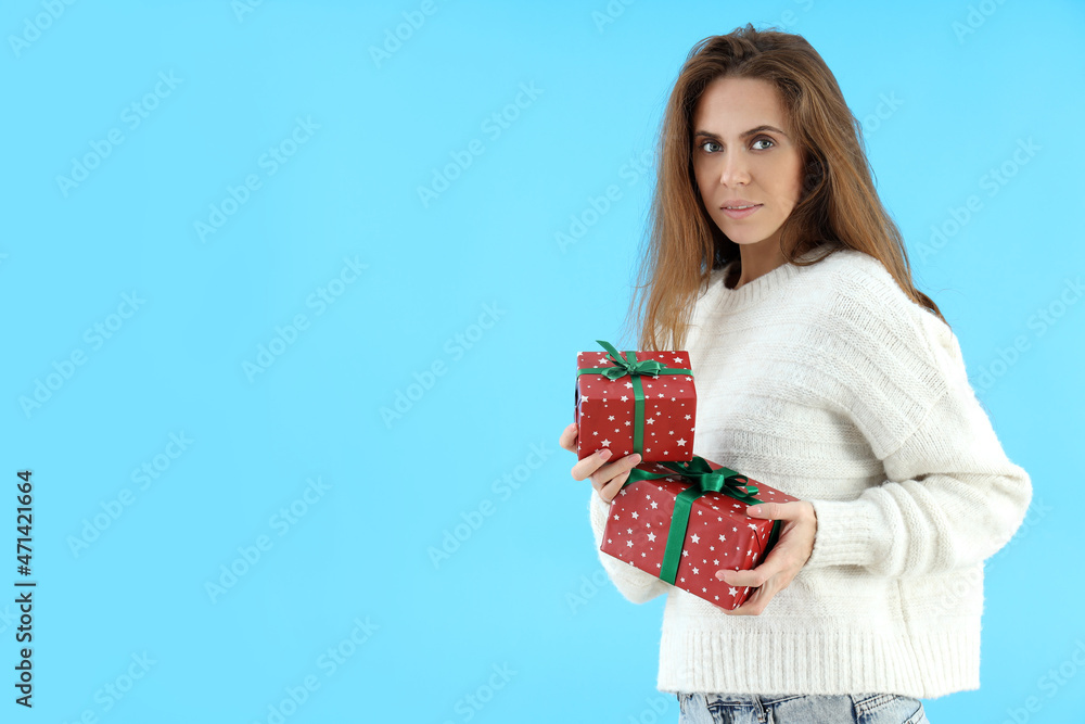 Attractive woman holds gift boxes on blue background Attractive woman holds gift boxes on blue background