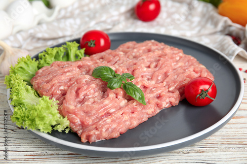Raw chicken minced meat with basil and vegetables on white wooden table, closeup