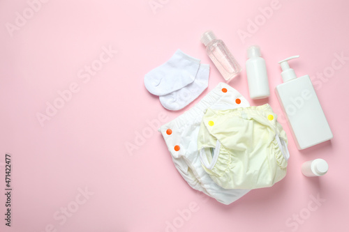 Concept of baby clothes with reusable diapers on pink background
