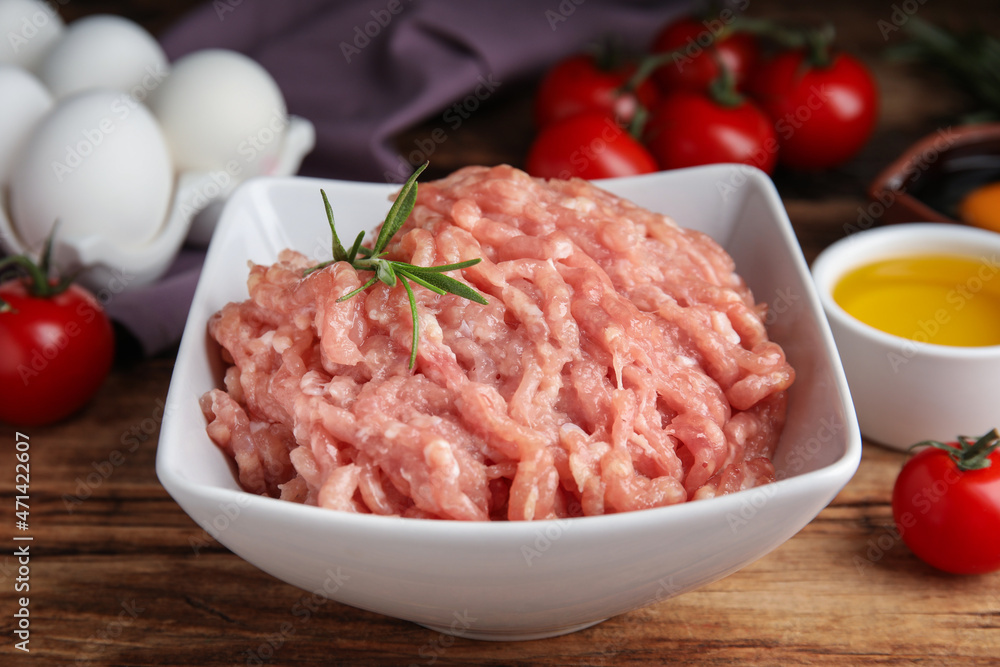 Raw chicken minced meat with rosemary on wooden table, closeup Raw chicken minced meat with rosemary on wooden table, closeup